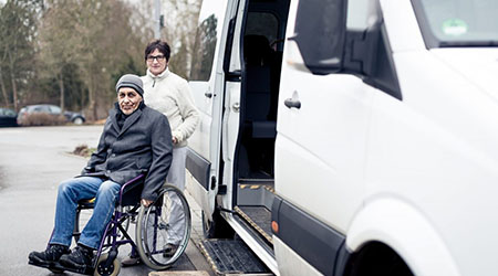 Man in wheelchair smiling beside a van