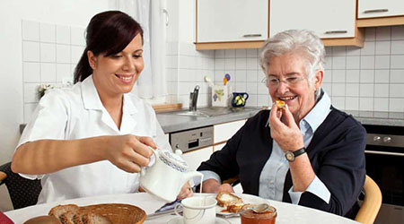 Carer serving tea elderly